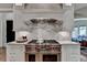 Bright kitchen features a professional range, marble backsplash and custom cabinetry at 962 Chattooga Trce, Suwanee, GA 30024