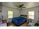 Bedroom with a blue comforter, ceiling fan, and two windows with blinds at 7427 W Fayetteville Rd, Riverdale, GA 30296