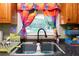 Modern kitchen sink with a black faucet and colorful window curtains at 705 Inglewood Se Dr, Smyrna, GA 30080