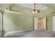 Main bedroom with grey carpet, tray ceiling, and access to another room at 5425 Edinbourgh Ct, Cumming, GA 30040