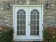 White double French doors leading to the basement, set in a stone wall at 2112 Bradford Pear Se Cir, Conyers, GA 30013