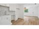 White kitchen cabinets and mosaic backsplash open to living area at 1410 Elizabeth Sw Ave, Atlanta, GA 30310