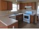 L-shaped kitchen with wood cabinets and white appliances at 435 Victoria Blvd, Oxford, GA 30054
