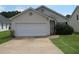 Beige house with a white garage door and well-maintained lawn at 435 Victoria Blvd, Oxford, GA 30054