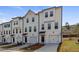 Row of three-story townhouses with white siding and attached garages at 77 Werner Brook Way, Atlanta, GA 30354