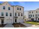 Three story townhouse with white siding, two-car garage, and landscaping at 77 Werner Brook Way, Atlanta, GA 30354