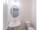 Simple bathroom with pedestal sink, toilet and round mirror at 7745 Squire Ct, Fairburn, GA 30213