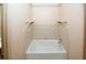 Small bathroom with single bathtub and wall-mounted shelving at 2994 Ravenwolfe Way, Snellville, GA 30039