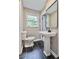 Updated bathroom with pedestal sink and dark tile floor at 6733 Walker Rd, Riverdale, GA 30296