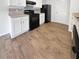 Modern kitchen with white cabinets, black appliances, and wood-look flooring at 725 Georgetown Ct, Jonesboro, GA 30236