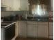 Galley kitchen with white cabinets, stove and double sink at 4356 Housworth Dr, Stonecrest, GA 30038
