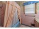Pink tiled bathroom with tub and shower curtain at 1645 Highpoint Rd, Snellville, GA 30078