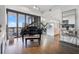 Spacious living room with grand piano, hardwood floors, and access to a balcony with city views at 3107 Peachtree Ne Rd # 1101, Atlanta, GA 30305