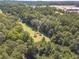 Aerial view showing home nestled in lush trees, with open areas nearby at 990 Bramlett Shoals Rd, Lawrenceville, GA 30045
