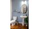 Modern bathroom with patterned wallpaper, pedestal sink, and toilet at 9931 Mancunian Way, Douglasville, GA 30135
