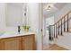 Modern powder room with wood vanity, stylish mirror, and view of staircase at 1972 Peeler Rd, Atlanta, GA 30338