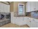 Bright laundry room with white cabinets, granite countertop and tile backsplash at 2145 Jones Phillips Rd, Dacula, GA 30019