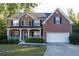 Brick two-story house with a white garage door and landscaping at 994 Rolling Forest Ln, Lilburn, GA 30047