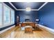 Home office with dark blue walls, wood floors, a desk, and windows at 4010 Toulon Ln, Cumming, GA 30040