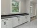 Bright laundry room with white cabinets, dark countertop, and built-in shelving at 7620 Breeze Bay Rd, Cumming, GA 30041