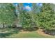 Wooded backyard with lake view and lush green grass at 7280 Timber Trl, Cumming, GA 30041