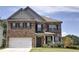 Brick two-story house with a large white garage door and landscaped lawn at 222 Gallant Fox Way, Acworth, GA 30102