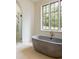 Concrete freestanding tub in a bright bathroom at 8350 Farmette Bnd, Chattahoochee Hills, GA 30268