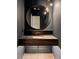 Stylish powder room with a dark vanity and round mirror at 8350 Farmette Bnd, Chattahoochee Hills, GA 30268
