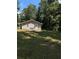 Back exterior view of a single-story gray home with a grassy backyard and surrounding trees at 130 Taunton Rd, Covington, GA 30014