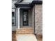 Front entryway featuring a black door, stone steps, and brick exterior at 5544 Whispering Swan Ct, Douglasville, GA 30135