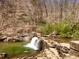 Small waterfall flowing over rocks in a wooded setting at 2415 Autumn Wind Drive - Lot 33, Dacula, GA 30019