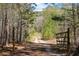 Gravel driveway leading into a wooded area with a gate at 7790 Atlanta Newnan Rd, Chattahoochee Hills, GA 30268