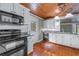 Kitchen boasts wood ceiling, white cabinets, and black appliances at 150 E Main St, Rutledge, GA 30663