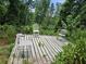 Small wooden deck with three chairs, surrounded by trees and vegetation at 2010 Driftwood Cir, Cumming, GA 30041