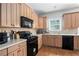Modern kitchen with light wood cabinets, black appliances, and tile backsplash at 421 Bedford Xing, Mcdonough, GA 30253