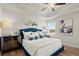 Well-lit bedroom with blue tufted headboard, ceiling fan, and hardwood-style flooring at 952 Elwood St, Dacula, GA 30019