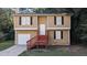 Tan two-story house with red stairs and attached garage at 5300 Forest Downs Ln, Atlanta, GA 30349