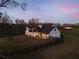 Two story white farmhouse with black roof and large backyard at dusk at 4165 Milford Trl, Cumming, GA 30028