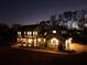 Stunning farmhouse exterior at night, showcasing a large front porch and well-manicured lawn at 4165 Milford Trl, Cumming, GA 30028