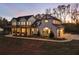 Two story white farmhouse with black metal roof and large yard at dusk at 4165 Milford Trl, Cumming, GA 30028