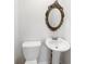 Small bathroom with pedestal sink, toilet, and ornate mirror at 211 Murphy Ave, Lawrenceville, GA 30044