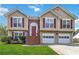 Two-story home with tan siding, red door, and two-car garage at 1055 Leighs Brook Way, Dacula, GA 30019