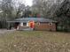 Brick ranch house with red door, landscaped yard, and driveway at 207 Howell Dr, Atlanta, GA 30331