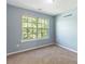 Well-lit bedroom featuring a large window, carpet, and neutral walls at 1467 Riverrock Trl, Riverdale, GA 30296