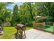 Relaxing patio with smoker, umbrella, and green lawn at 174 Rivertown Rd, Fairburn, GA 30213