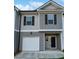 Two-story townhome with gray siding, white garage door, and black front door at 5120 Lower Elm St, Atlanta, GA 30349