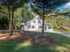 White farmhouse nestled in trees with a large rock and manicured lawn at 3563 Denby Dr, Snellville, GA 30039