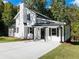 White farmhouse with black accents, a covered porch, and a landscaped yard at 3563 Denby Dr, Snellville, GA 30039