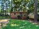 Brick cottage with a small front yard, steps to the entrance and mature trees surrounding the property at 435 Warren Ave, Scottdale, GA 30079