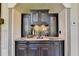 Elegant wet bar with granite countertop, dark cabinetry, and glass-front doors at 6308 Woodlake Dr, Buford, GA 30518